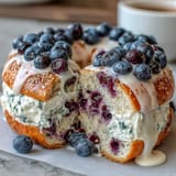 A stack of chewy blueberry protein bagels topped with creamy Greek yogurt frosting, perfect for a healthy breakfast.  