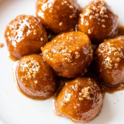 Sweet, glazed Candied Yams glistening after baking, offering a warm spiced aroma and delicious taste.