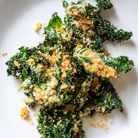 A close-up of vibrant kale salad tossed in garlic Parmesan dressing, topped with golden toasted breadcrumbs and shaved cheese.