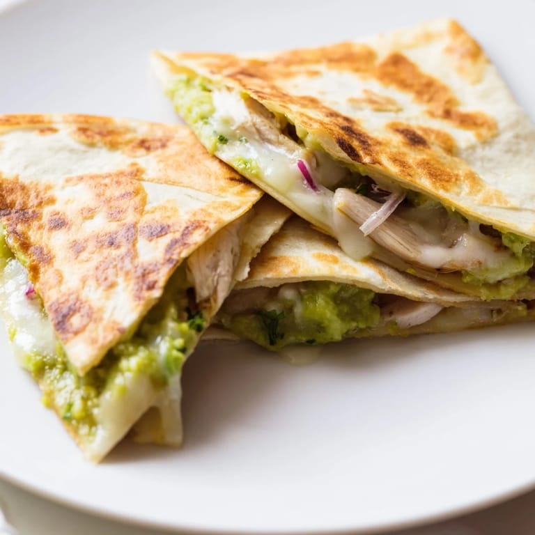 Freshly cooked Chicken Avocado Quesadilla served warm, with melted cheese oozing from the edges and red onion slices.